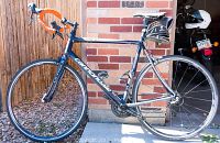 Full side view of dark blue Cannondale Synapse bicycle showing frame, wheels, handlebars and attached accessories