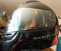 Side view of black Harley-Davidson helmet with white logo and clear visor.