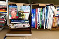 Photo showing two boxes filled with various children's books, arranged vertically and horizontally with some visible titles and colorful spines.