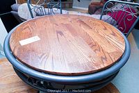 Close-up of round wooden table surface showing wood grain and metal frame edge.