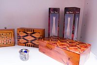Three handmade wooden boxes with detailed geometric inlay patterns, two boxed bud vases, and a small decorative silver container.