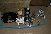Overview of mechanical toys including Roboraptor, MiP robot in box, T-Rex and silver dinosaur with zebra stripes, controllers, manuals and toy arena.