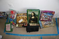 Photo showing various games and puzzles placed on the floor including Trivial Pursuit Star Wars, Mona Lisa jigsaw puzzle, Shogun puzzle, and an animal-themed 1000-piece puzzle.