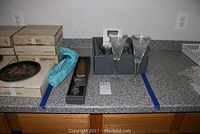 Counter setup with four boxes, two Waterford crystal toasting flutes outside their box, and a crystal cake server in box.