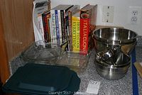 Full view of the collection showing Pyrex baking dishes, stainless steel mixing bowls, cookbooks lined up behind, and recipe card box in front