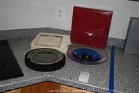 Two collectible art glass pieces shown on a kitchen counter, including a Morgantown Crystal etched plate with certificate and a blue Orrefors glass bowl with box.
