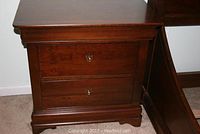 Front and side view showing one nightstand with two drawers closed, highlights dark wood finish and brass handles.