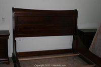 Front view of dark wood sleigh bed headboard and part of footboard, showing curved sleigh style design.