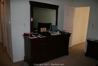 Dark wood dresser with eight drawers and matching mirror on top, showing full front view with some small items on surface.