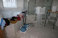 Bathroom corner showing tub, humidifiers on floor, hairdryers and other accessories on tub ledge