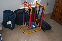 Overall view of elliptical machine with two rolled sleeping bags and three mats around it