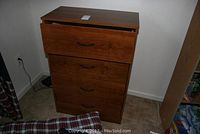 Four drawer wooden dresser with medium brown finish and black curved handles
