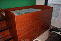 Full side view of cherry-finish loft bed showing raised platform, guardrails and drawer bank below.