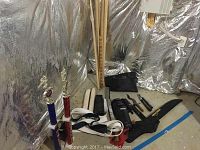 Photo showing martial arts trophies, white belts, a knife, and a black carrying case with 'Top Ten' branding on the floor in a metallic insulated room.