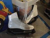 Pair of white ice skates with black blades and white laces