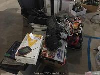 View of pile containing stacked toy keyboards, computer accessories, cables, and a handheld device on boxes in a dimly lit area.
