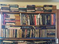 Wide view of multiple shelves filled with hardcover and paperback books from various genres related to mysteries and ancient history
