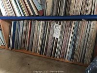 Shelf containing densely packed vinyl record albums in various cover colors and conditions.