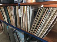 Shelf holding over 50 vinyl record albums with visible titles and artists on the spines, many classical music albums.