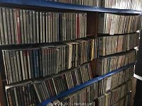 Shelf of vertically stacked CDs in jewel cases and paper sleeves