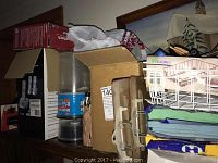 Photo showing Panasonic cordless phone box, wire basket with office supplies, white desk trays, clipboards, and Hammer mill paper reams on a shelf.