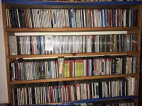 Full view of wooden shelves fully stocked with a large collection of assorted CDs from multiple genres and artists.