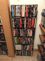 Full view of black metal storage rack filled with assorted DVDs arranged on six shelves