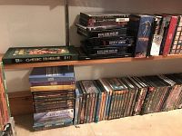 Two shelves of DVD cases arranged in rows, showing various box sets and single-disc titles