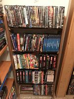 Full view of the wooden rack filled with DVDs showing multiple types and titles across five shelves.