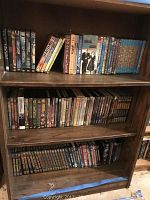 Full bookshelf view with all DVDs arranged on three shelves showing variety and quantity of the collection.