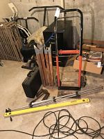View of the red and black hand dolly with sturdy wheels standing next to black storage case and various tools in basement setting.
