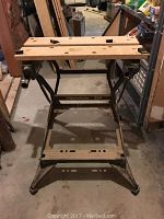 Front view of the Black and Decker Workmate 200 wooden top and black metal frame, showing the working surface with holes and slots for clamping.