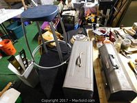 Photo showing the shop stool and two metal tool boxes on a table alongside various tools and items.
