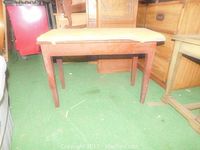 Front view of the wooden bench with beige padded seat, showing four legs and sturdy construction.