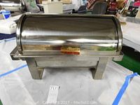 Front view of the chrome buffet server with closed roll-top lid showing rectangular base and brass plaque.