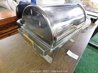 Photo of chrome buffet server with closed roll-top lid showing gold-tone handle and front side.