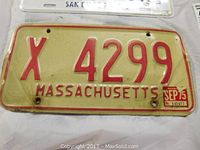 Massachusetts license plate with red embossed characters 'X 4299' and SEP 75 sticker, showing wear and rust spots.