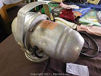 Side view of metal fog generator showing wear and attached power cord.