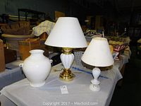 Photo of large white ceramic vase and two white table lamps on a table.