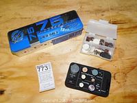 Blue Dremel 75 Accessories metal box with two small plastic cases containing various rotary tool attachments and a MaxSold auction tag.