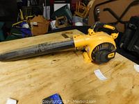 Side view of yellow Poulan Pro blower vac lying on a wooden surface showing the full length and black blower tube.