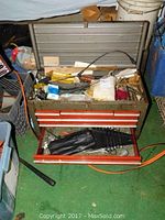 Open large metal toolbox showing contents including various tools and parts inside drawers and top compartment.