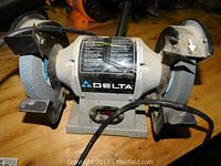 Front view of the Delta bench grinder showing both grinding wheels and Delta branding on the front.