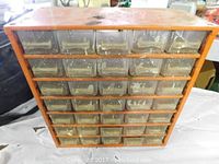 Front view of orange metal workshop storage container with 42 clear drawers showing dust and dirt, used for small part storage.