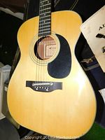 Close-up of the Kent acoustic guitar body and strings, showing natural wood finish and black pickguard.