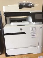 Full front and side view of printer on wooden surface showing paper trays, ADF and touchscreen