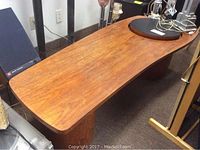 Kidney-shaped teak coffee table top in full view showing wood grain and overall finish.