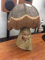 Full view of the lamp showing the woman figure base and cane fringe lamp shade.