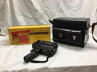 Photo showing Elmo Super 8 Sound Camera with hand strap, black leather carrying case and original yellow box of Brownie Movie Titler Outfit