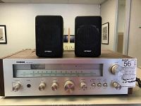 Front view of Audio Reflex AR-620 receiver showing silver face with tuning dial and two Optimus mini speakers on top.